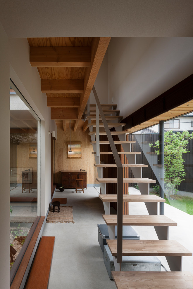 Ejemplo de escalera recta de estilo zen sin contrahuella con escalones de madera y barandilla de metal