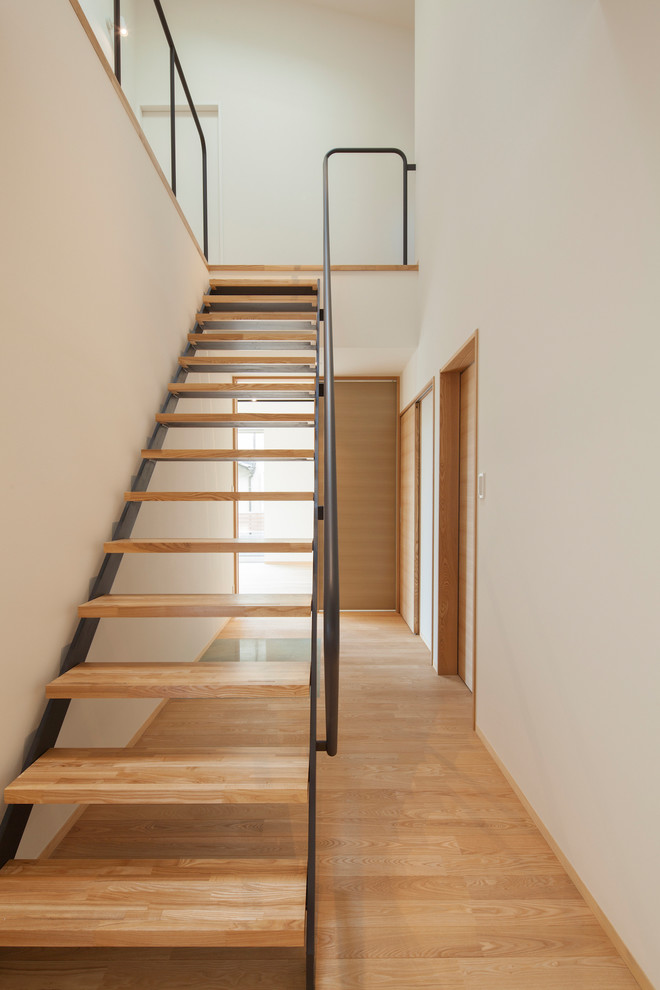 Immagine di una scala a rampa dritta design con pedata in legno, nessuna alzata e parapetto in metallo