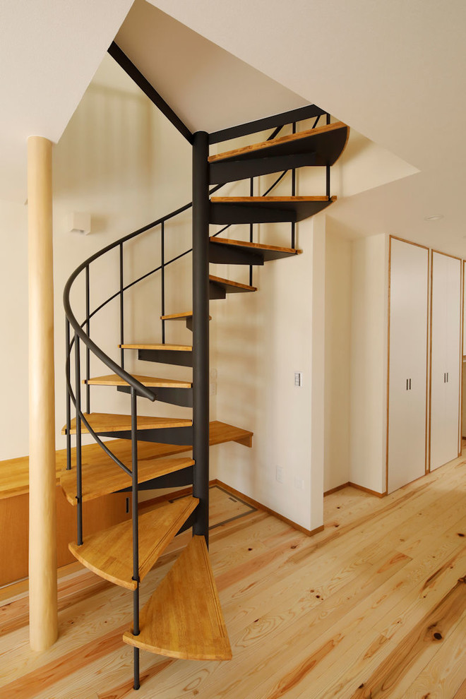 На фото: винтовая лестница среднего размера в восточном стиле с деревянными ступенями и металлическими перилами без подступенок с