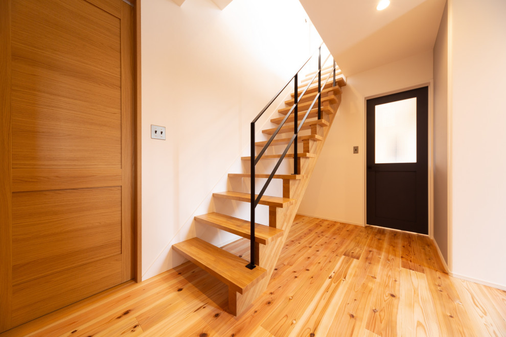 Ejemplo de escalera recta de estilo zen sin contrahuella con escalones de madera, barandilla de metal y papel pintado