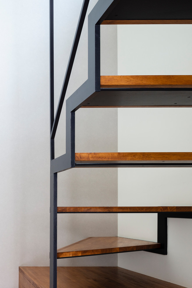 Cette photo montre un escalier sans contremarche moderne en U avec des marches en bois et un garde-corps en métal.
