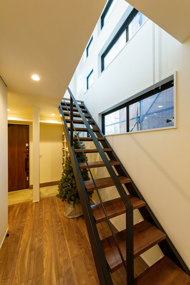 На фото: прямая лестница среднего размера в стиле модернизм с деревянными ступенями, металлическими перилами и обоями на стенах без подступенок