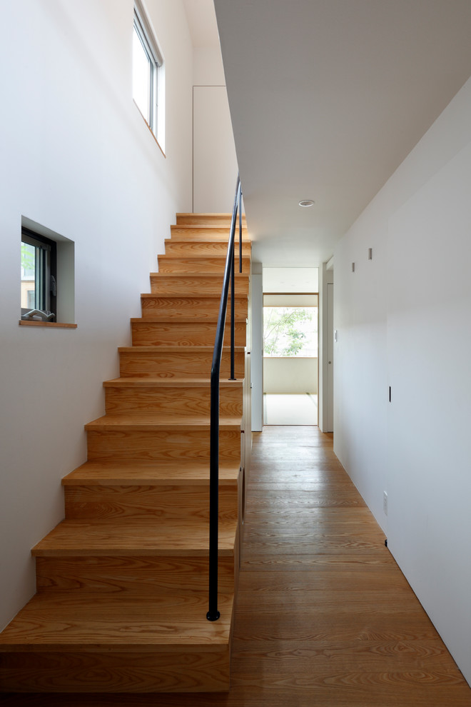 Cette image montre un escalier droit minimaliste avec des marches en bois, des contremarches en bois et un garde-corps en métal.