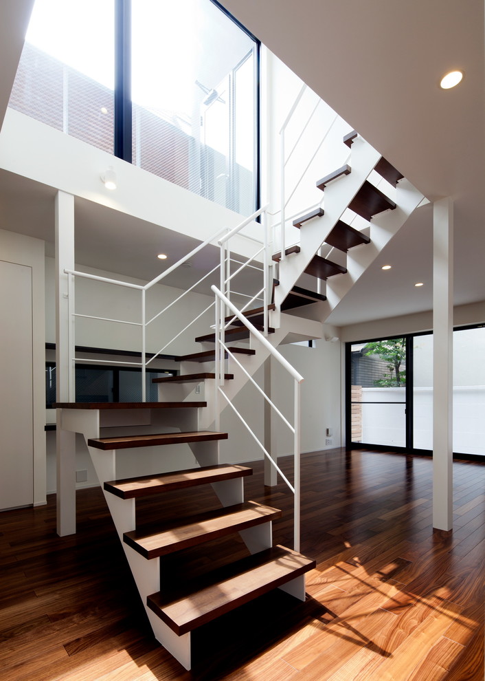 Idées déco pour un escalier courbe contemporain avec des marches en bois, des contremarches en moquette, un garde-corps en métal et éclairage.