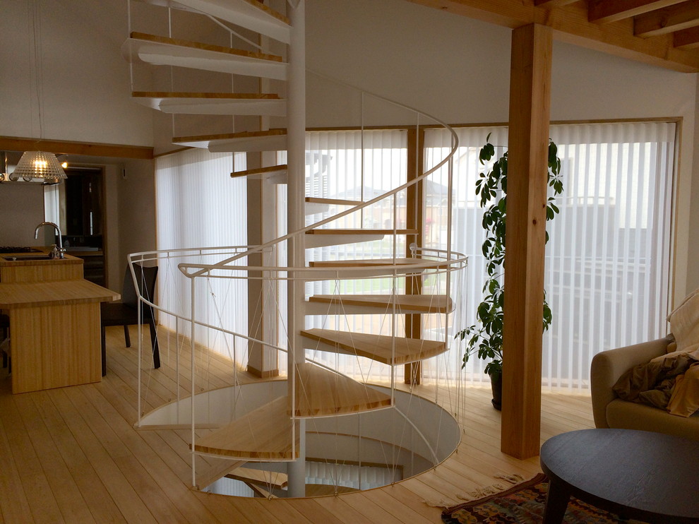 Cette photo montre un petit escalier sans contremarche hélicoïdal scandinave avec des marches en bois et un garde-corps en métal.
