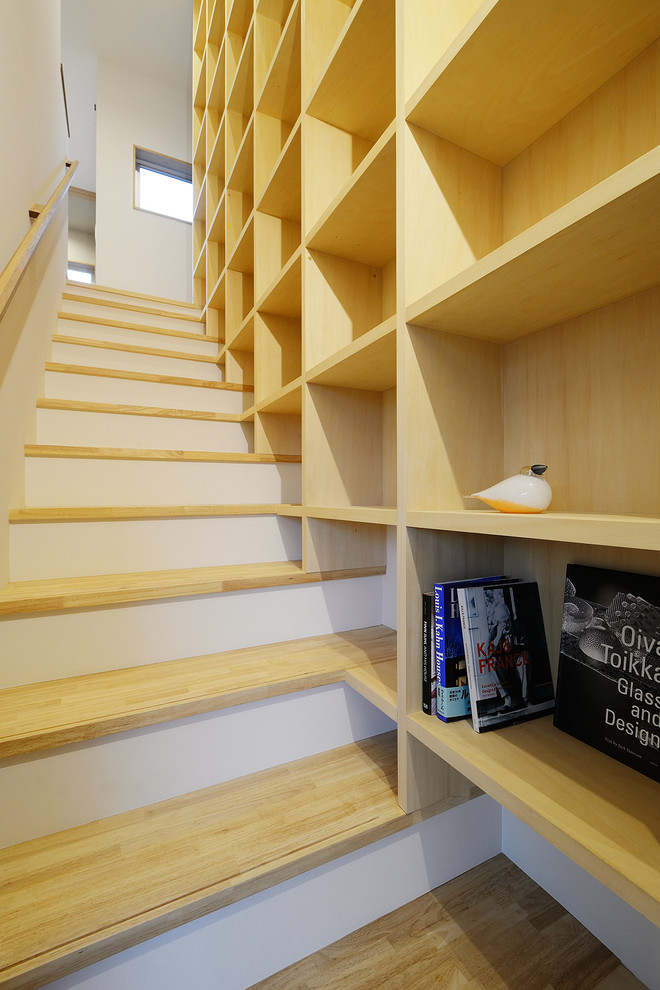 Imagen de escalera recta escandinava de tamaño medio con escalones de madera, barandilla de madera y papel pintado