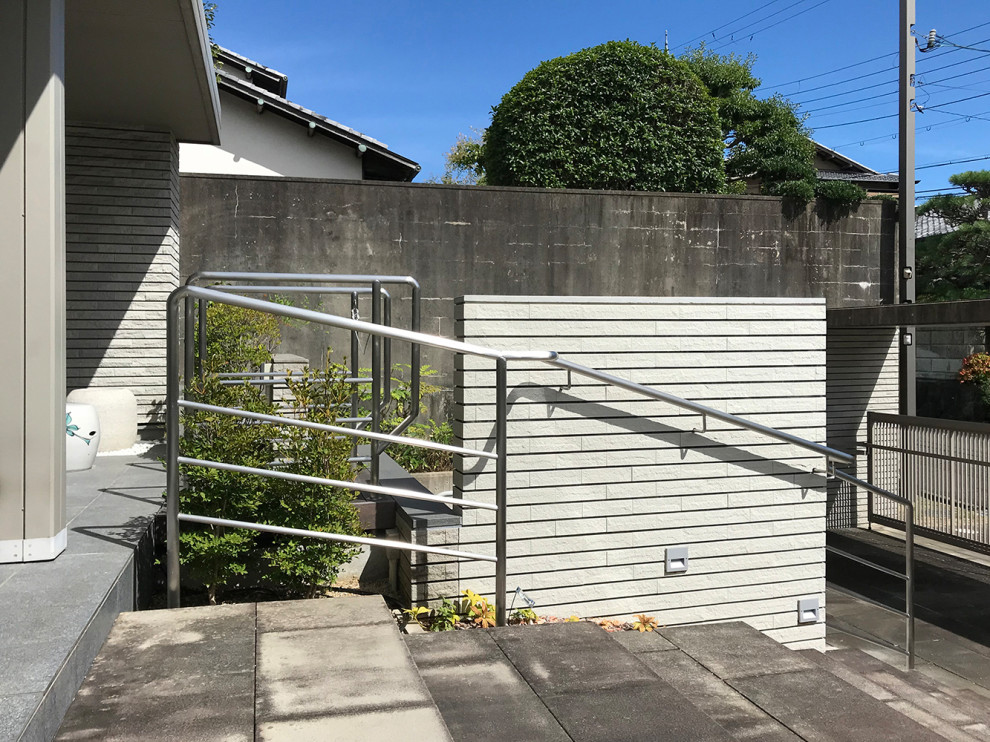 На фото: маленькая прямая бетонная лестница в стиле модернизм с ступенями из известняка и металлическими перилами для на участке и в саду с