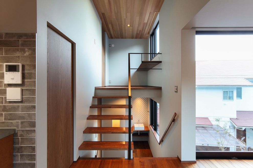Ejemplo de escalera en U de estilo zen sin contrahuella con escalones de madera y barandilla de metal