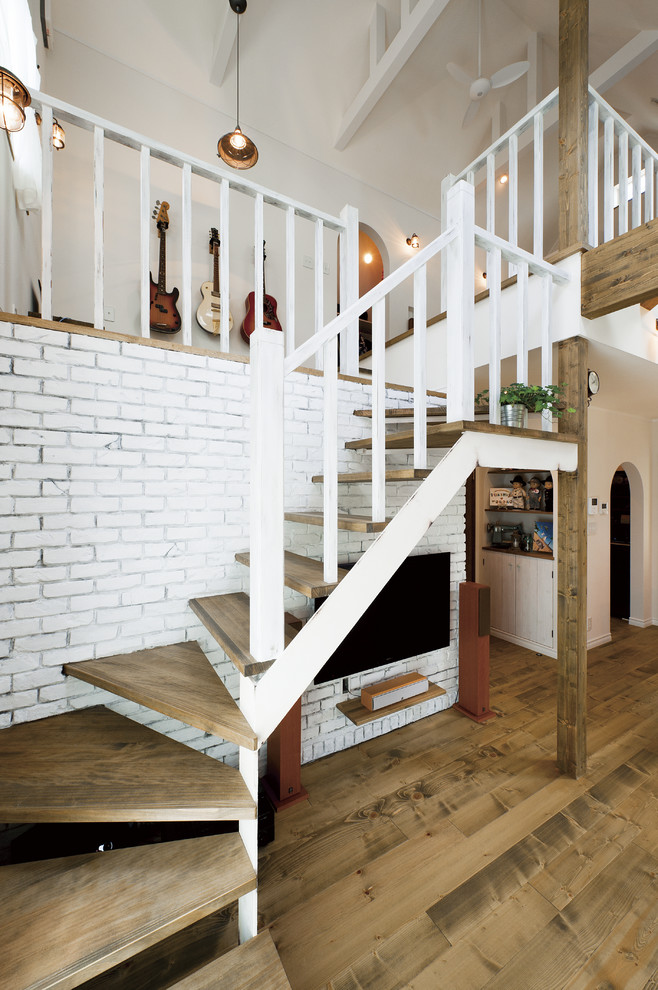 Réalisation d'un escalier sans contremarche courbe champêtre avec des marches en bois, un garde-corps en bois et un téléviseur en dessous.