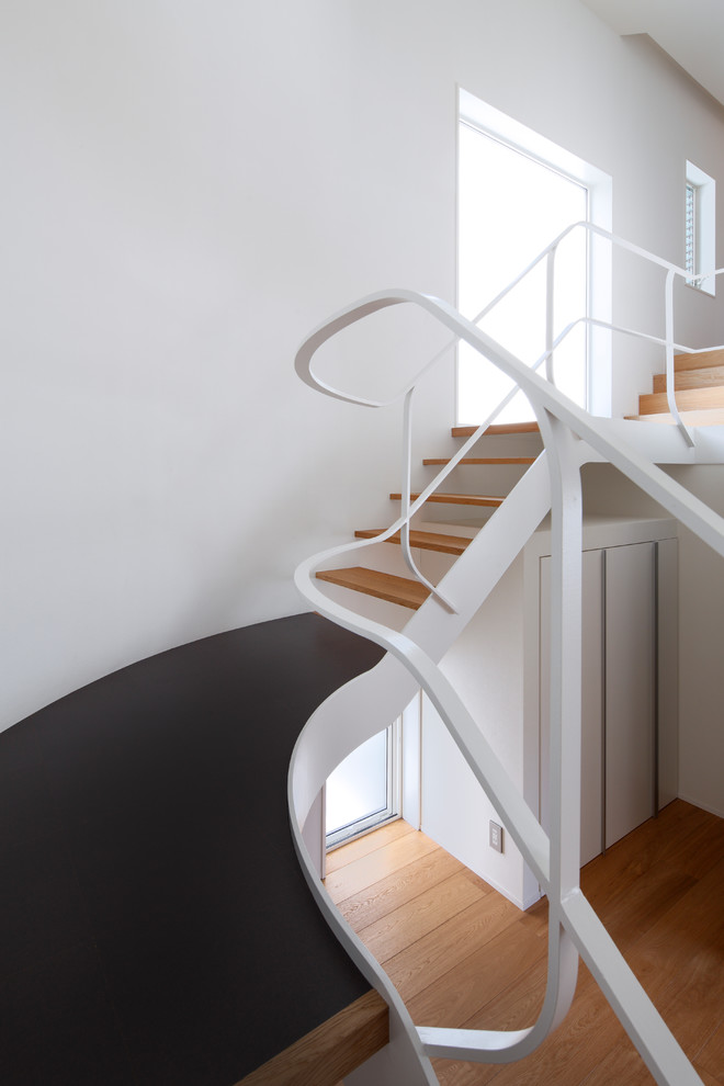 Пример оригинального дизайна: изогнутая деревянная лестница среднего размера в современном стиле с деревянными ступенями и металлическими перилами