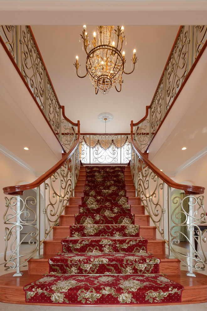 На фото: огромная п-образная деревянная лестница в классическом стиле с деревянными ступенями и деревянными перилами с