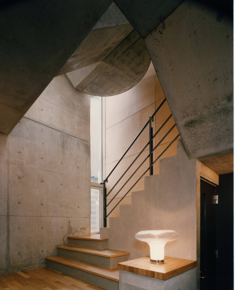 Aménagement d'un grand escalier courbe moderne avec des marches en bois, des contremarches en béton et un garde-corps en matériaux mixtes.
